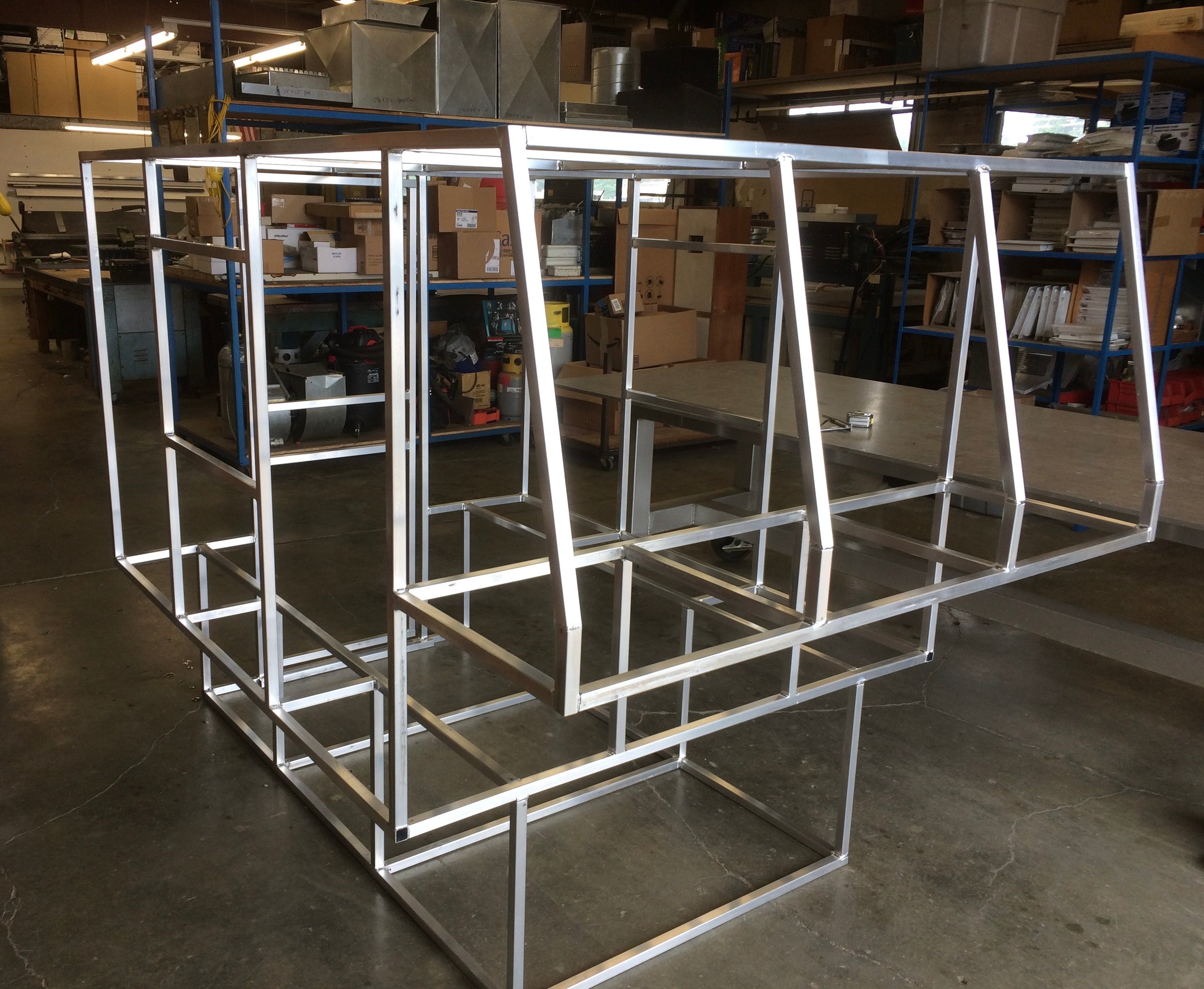 Metal frame structures in warehouse, awaiting assembly or further processing