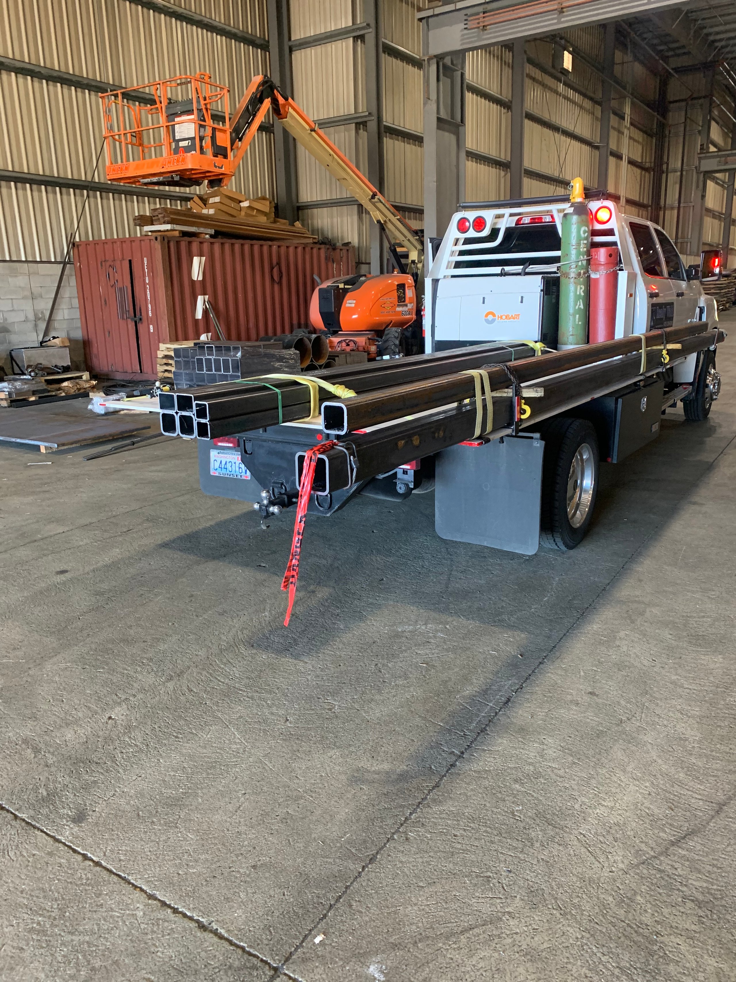 Orange lift and truck with metal pipes in industrial warehouse interior