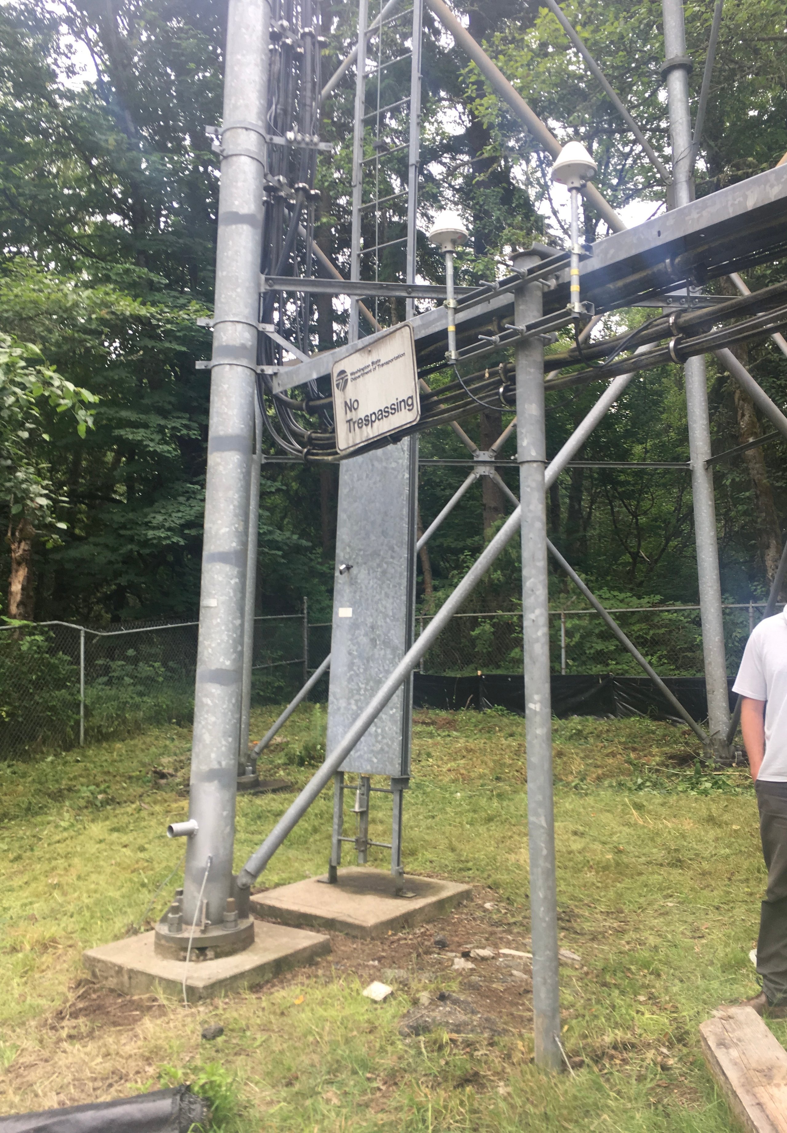 Communication tower with no trespassing sign in forested area